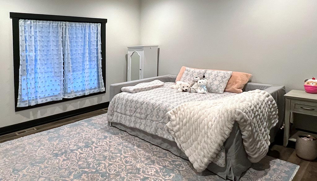 Photo of a light gray bedroom with a large area rug, a bed, and a large window