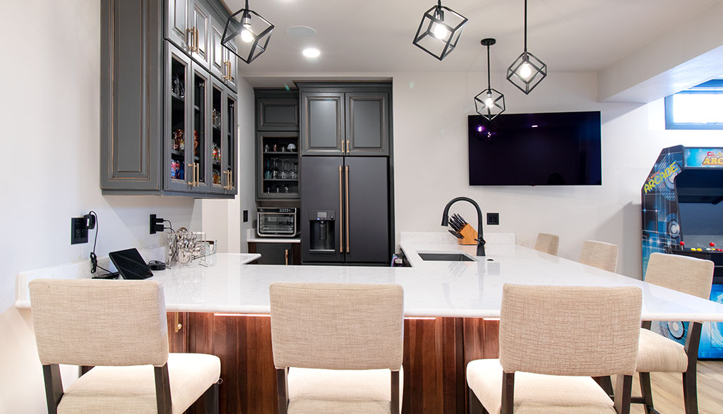 Kitchenette/bar area in basement with white counters, white fabric bar stools, gray cabinets, and matching appliances