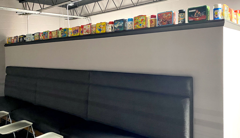Photo showing series of vintage lunchboxes displayed on top of ledge